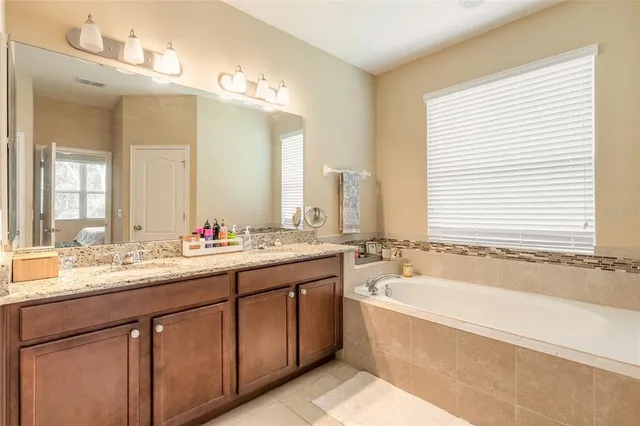 a bathroom with a granite countertop bathtub a double vanity sink and mirror