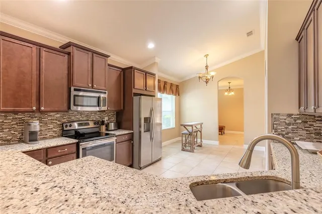 a kitchen with stainless steel appliances kitchen island granite countertop a sink refrigerator and cabinets