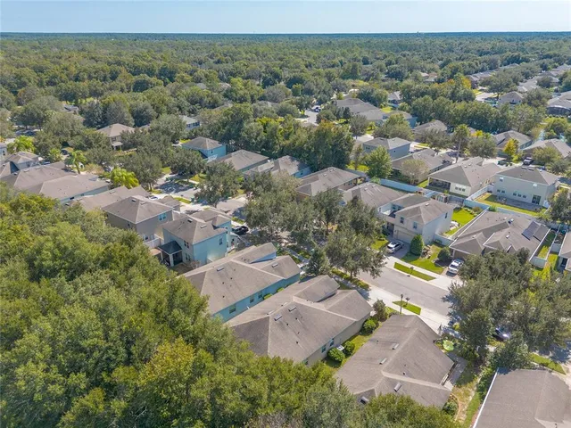 an aerial view of residential houses with outdoor space and trees