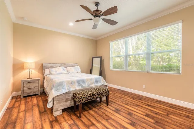 a bedroom with a bed and a large window with wooden floor