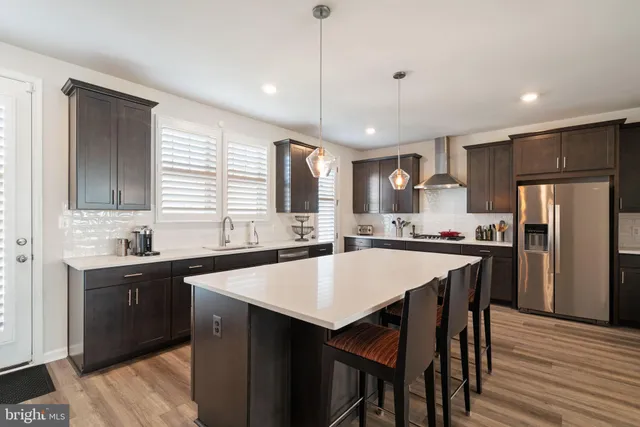 a kitchen with stainless steel appliances granite countertop a sink a stove a refrigerator and island with wooden floor