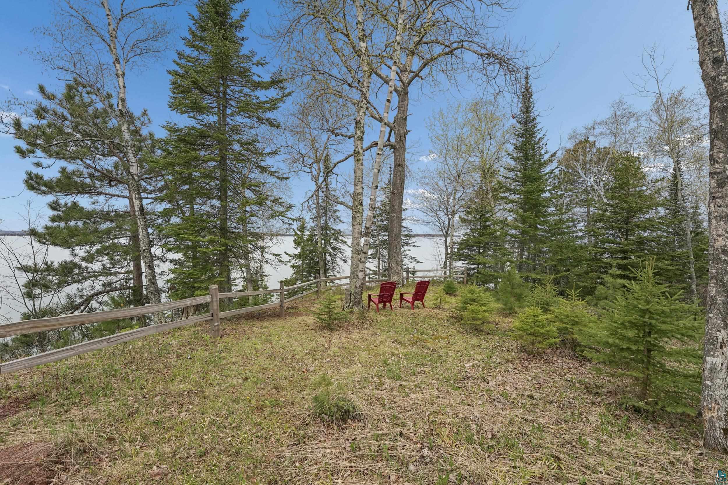 89095 West Romans Point Road Herbster, WI 54844 - Photo 6 of 30 Wood rail fence delineating the property boundary, featuring mature trees and established evergreens