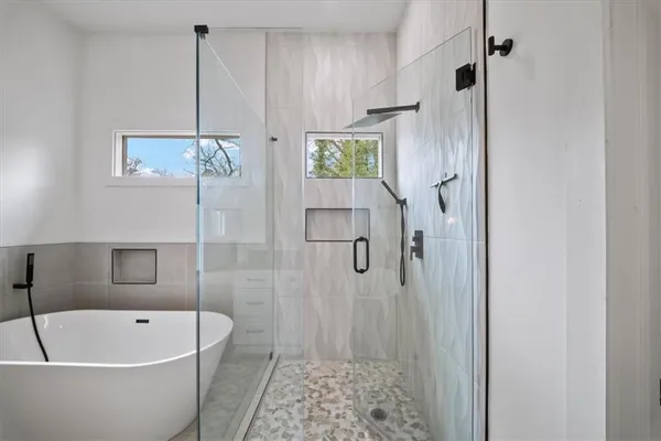 a bathroom with a bathtub a window and a shower