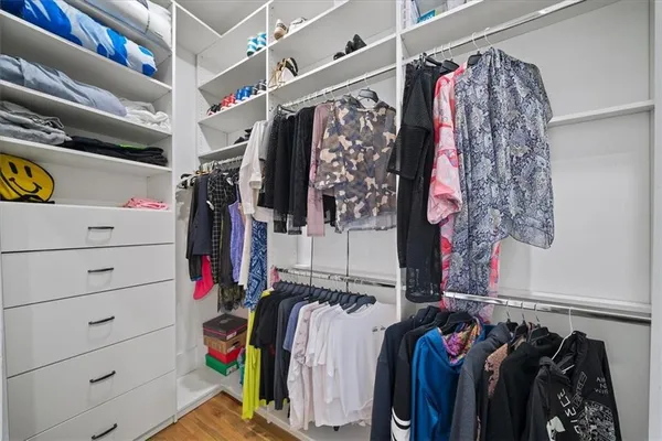 a view of walk in closet with clothes and shoes