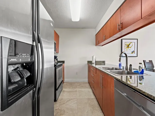 a kitchen with stainless steel appliances granite countertop a sink and a refrigerator