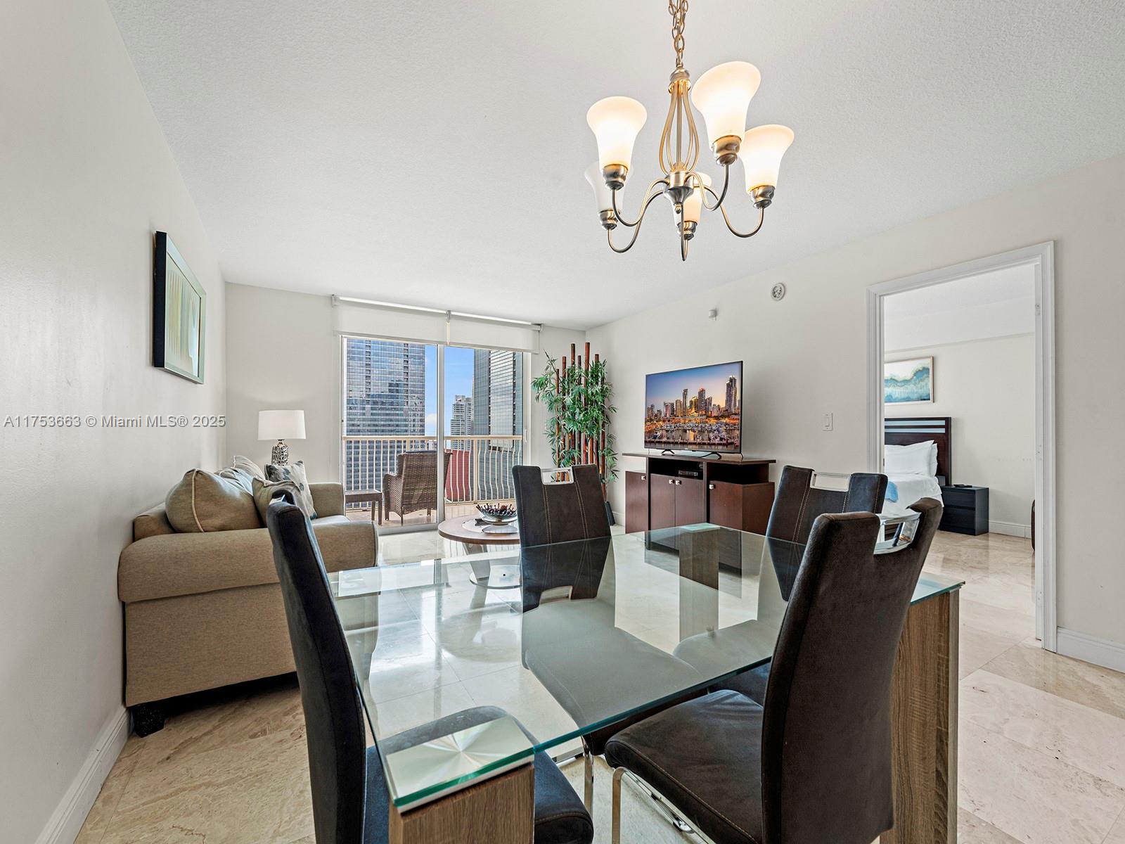 1200 Brickell Bay Drive, Unit 4019 Miami, FL 33131 - Photo 6 of 32 a view of a dining room with furniture a chandelier and wooden floor
