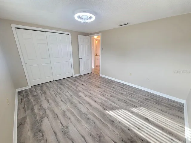 a view of an empty room with closet and a window