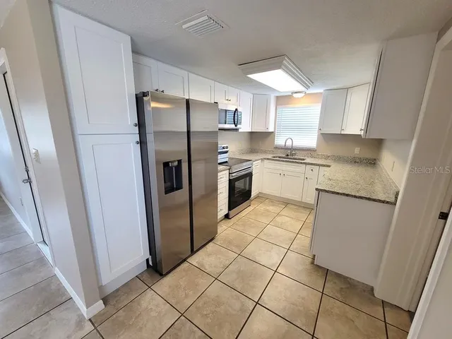 a kitchen with stainless steel appliances granite countertop a refrigerator and a stove top oven
