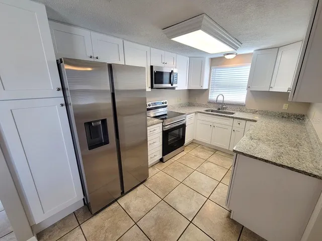 a kitchen with stainless steel appliances granite countertop a refrigerator sink and stove