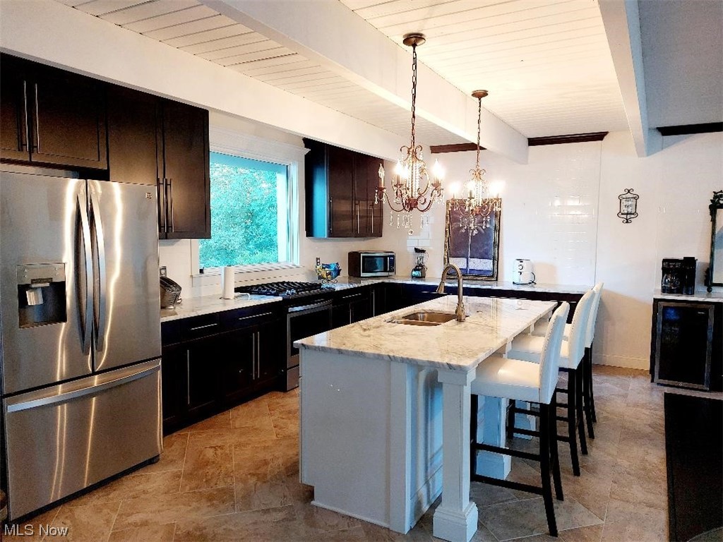 3061 Sandy Lake Road Ravenna, OH 44266 - Photo 5 of 15 Kitchen featuring appliances with stainless steel finishes, beamed ceiling, a center island, dark brown cabinetry, light countertops, and light tile floors