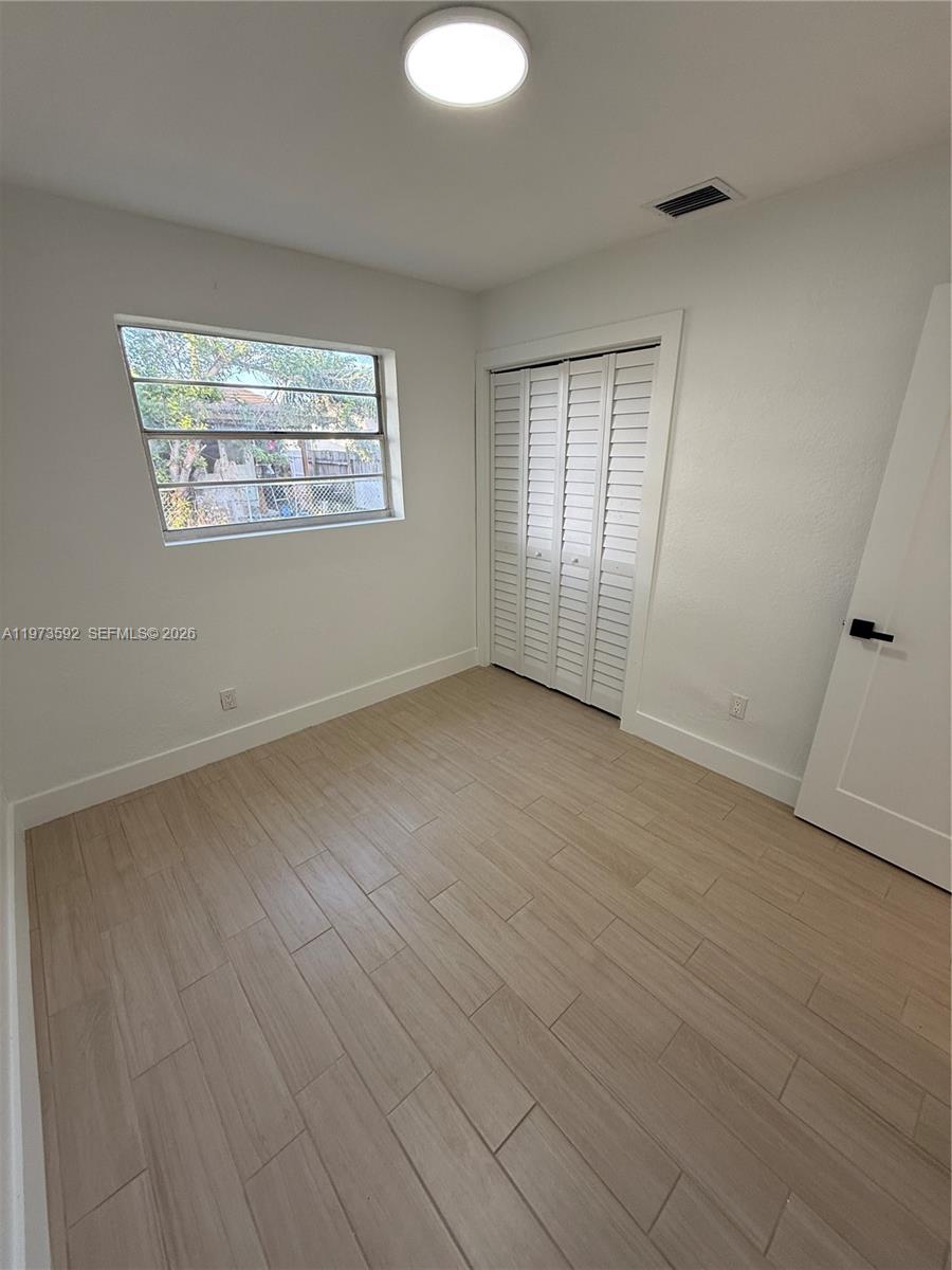 11063 Southwest 5th Street, Unit 11063 Sweetwater, FL 33174 - Photo 12 of 19 an empty room with wooden floor and windows
