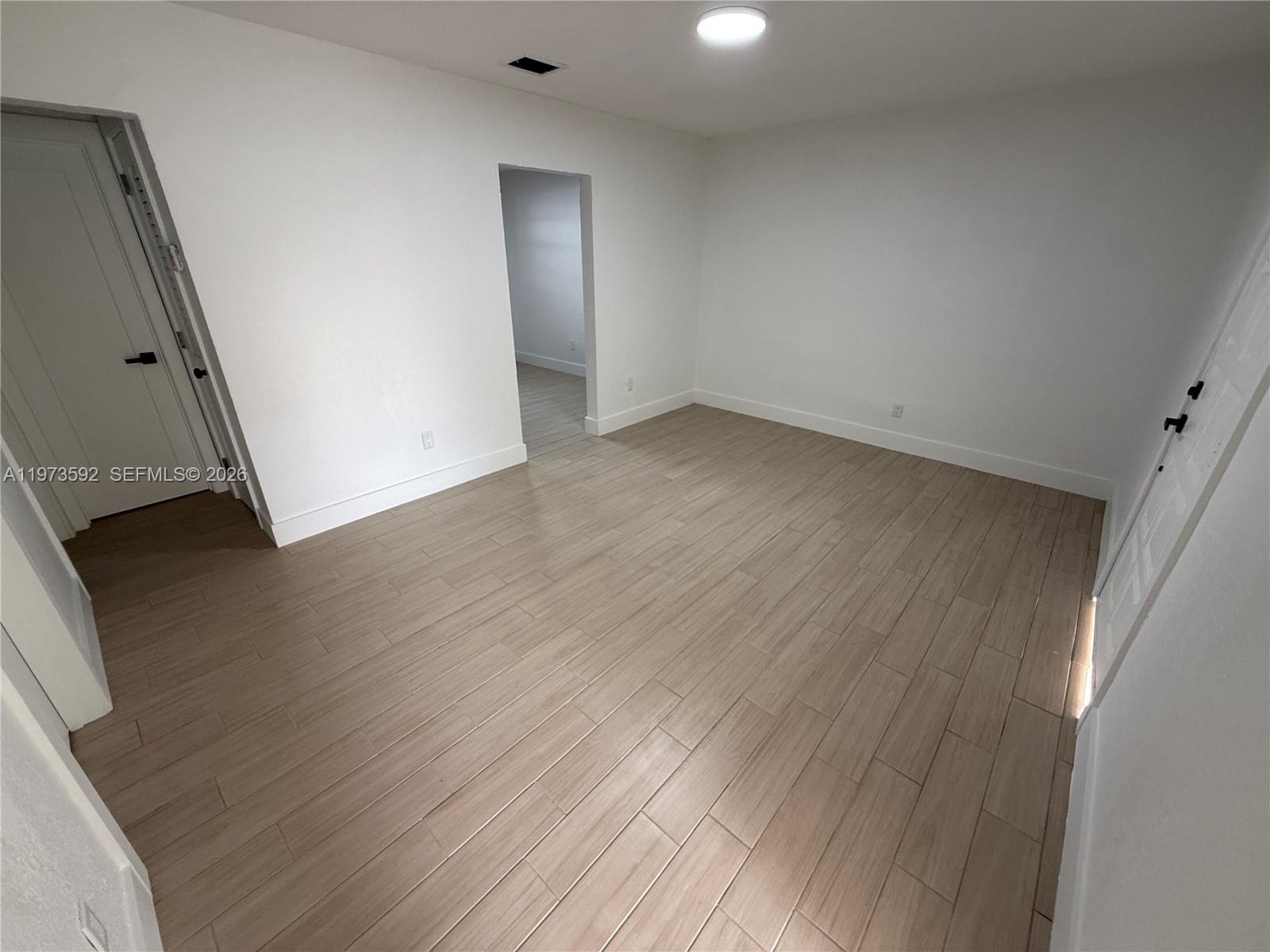 11063 Southwest 5th Street, Unit 11063 Sweetwater, FL 33174 - Photo 14 of 19 an empty room with wooden floor and a window