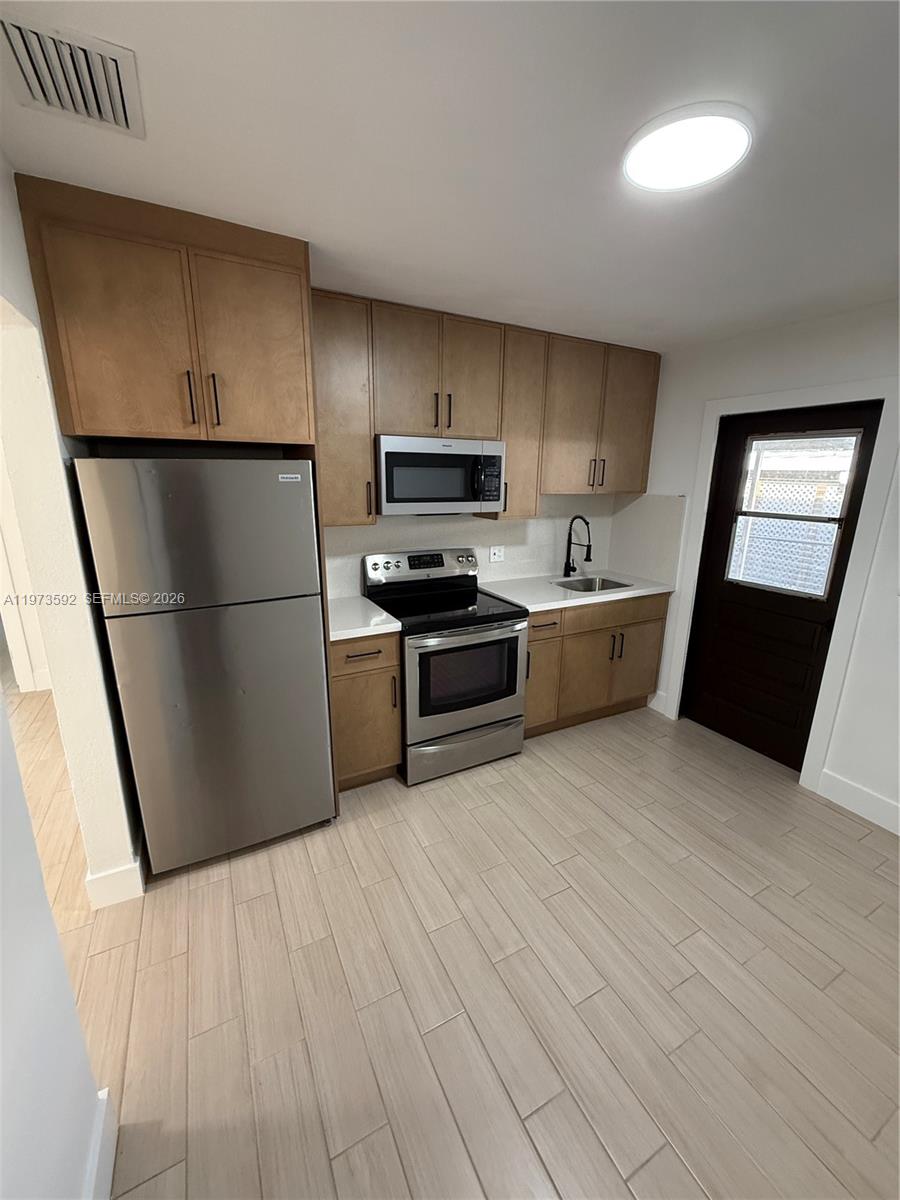 11063 Southwest 5th Street, Unit 11063 Sweetwater, FL 33174 - Photo 2 of 19 a kitchen with stainless steel appliances a refrigerator a sink a stove a microwave a sink and a refrigerator