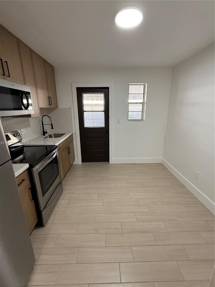 11063 Southwest 5th Street, Unit 11063 Sweetwater, FL 33174 - Photo 4 of 19 a kitchen with granite countertop a stove a sink and a refrigerator