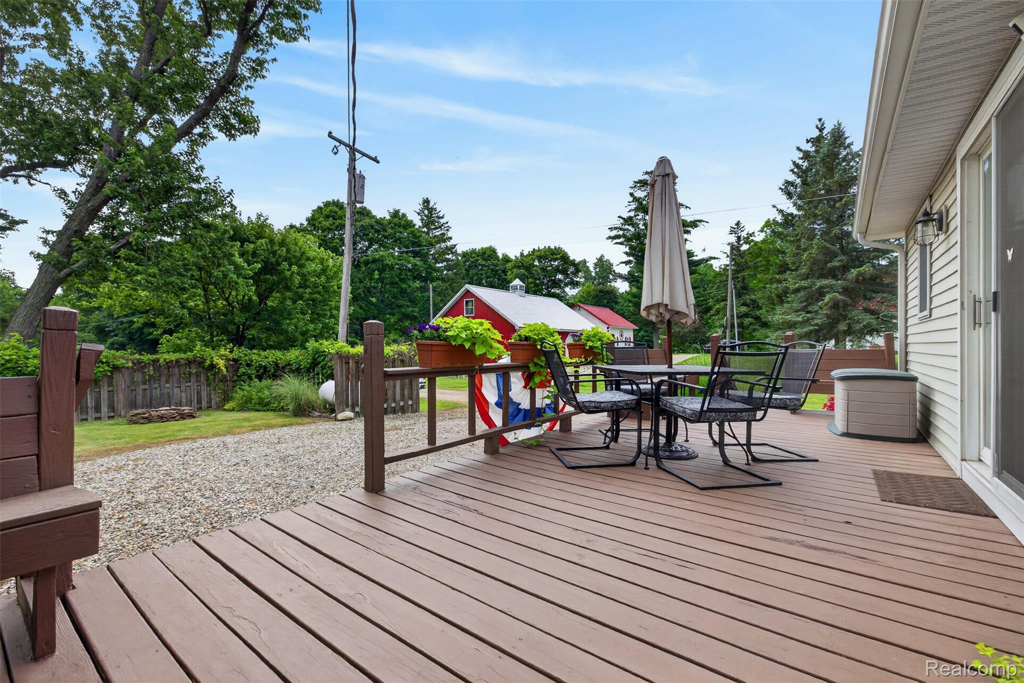 5977 Anglers Road Ortonville, MI 48462 - Photo 60 of 63 Expansive wood-finish deck with privacy railing, gravel patio space, and mature tree landscaping
