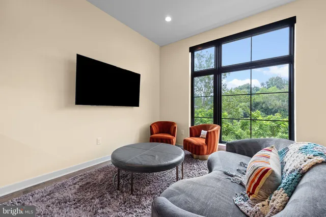 a living room with furniture a flat screen tv and a floor to ceiling window