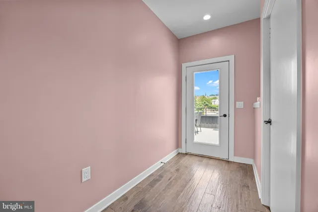 a view of an empty room with closet and wooden floor