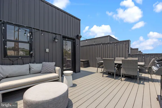 a view of a roof deck with table and chairs a barbeque with wooden floor and fence