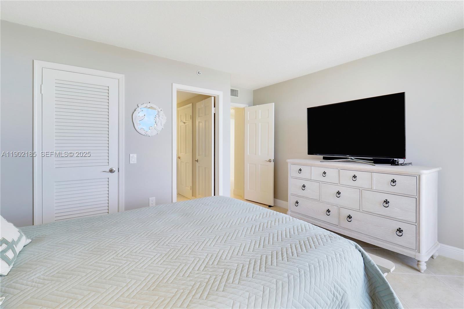 200 South Beach Road, Unit 703 Tequesta, FL 33469 - Photo 23 of 52 a bedroom with a bed and a flat screen tv in white walls