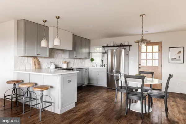 a kitchen with stainless steel appliances granite countertop a dining table chairs stove refrigerator and cabinets