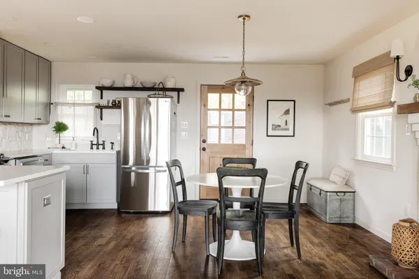 a kitchen with stainless steel appliances a dining table chairs a refrigerator and cabinets