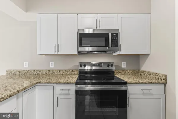 a kitchen with stainless steel appliances granite countertop white cabinets and a stove top oven