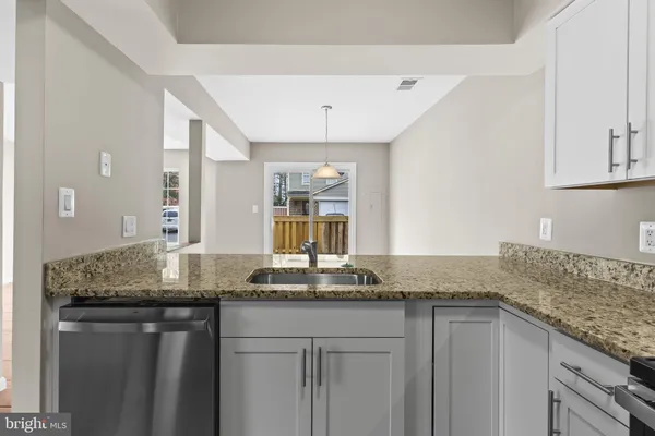 a kitchen with granite countertop a sink and white cabinets