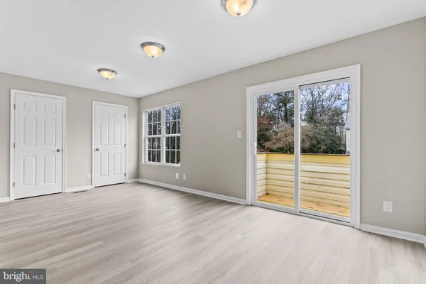 a view of an empty room with wooden floor and windows