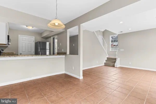 a view of an empty room with kitchen and window
