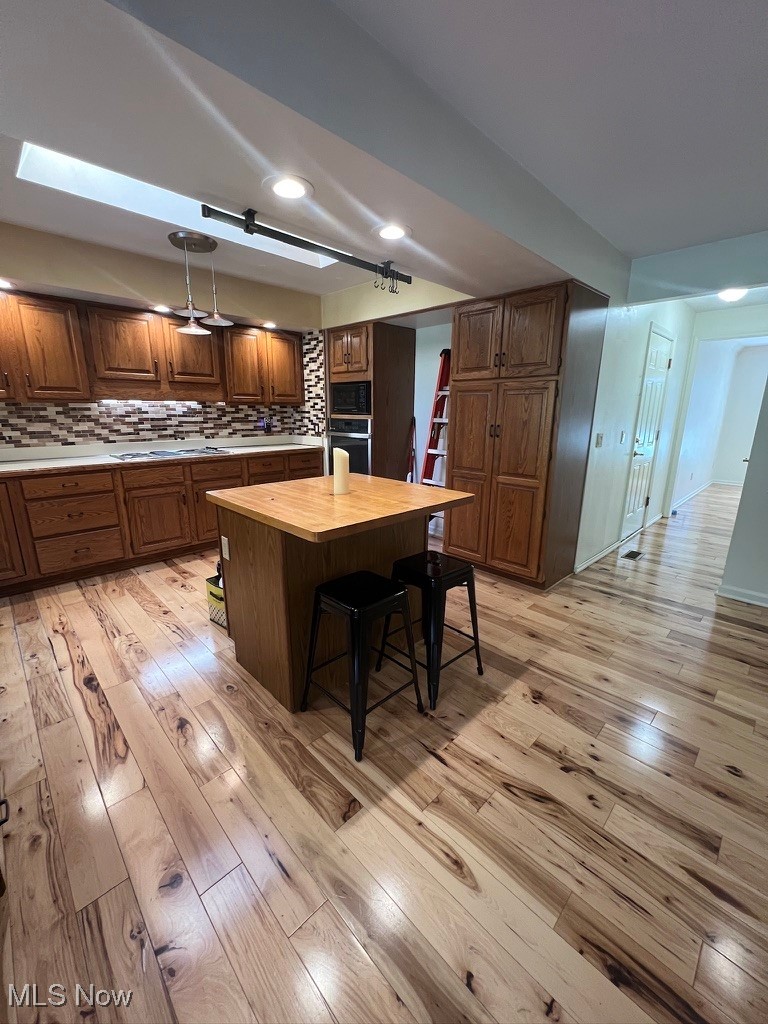 11331 Palmer Road Painesville, OH 44077 - Photo 10 of 47 Kitchen featuring light hardwood / wood-style floors, stainless steel oven, wood counters, backsplash, and a center island