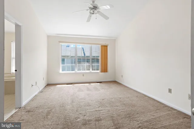 an empty room with a chandelier fan and windows