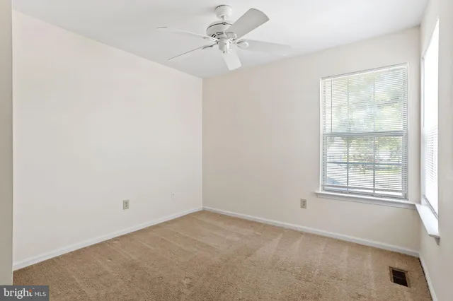 an empty room with windows and fan