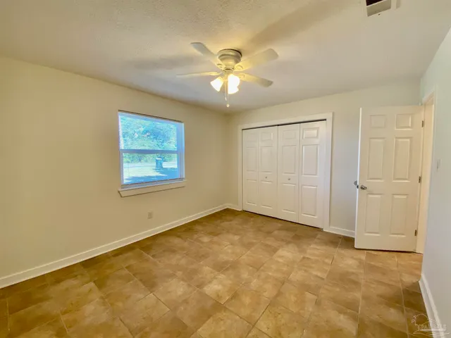 an empty room with a ceiling fan and a window