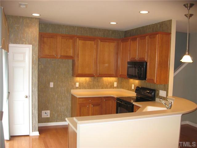 7025 Racine Way Raleigh, NC 27615 - Photo 4 of 7 The bright and open kitchen area includes beautiful countertops, undermount and accent lighting, wall coverings and a great little breakfast bar for that morning coffee or a quick bite to eat.