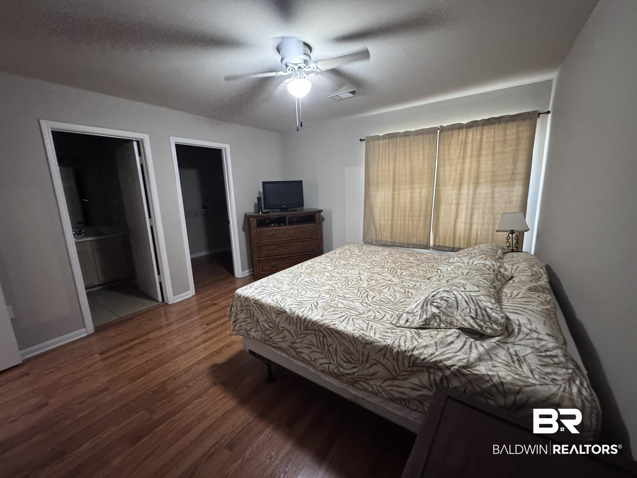 1517 Regency Road, Unit 131 Gulf Shores, AL 36542 - Photo 18 of 21 Bedroom with a walk in closet, dark wood-type flooring, a ceiling fan, and a textured ceiling