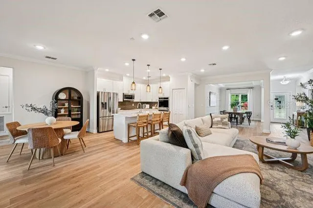 a living room with furniture kitchen view and a wooden floor