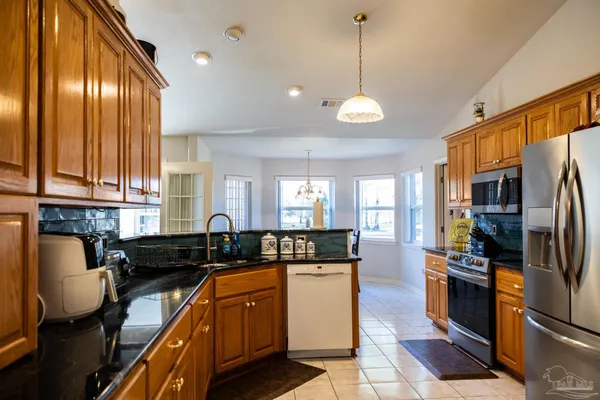 a large kitchen with stainless steel appliances granite countertop a stove a refrigerator a sink and dishwasher