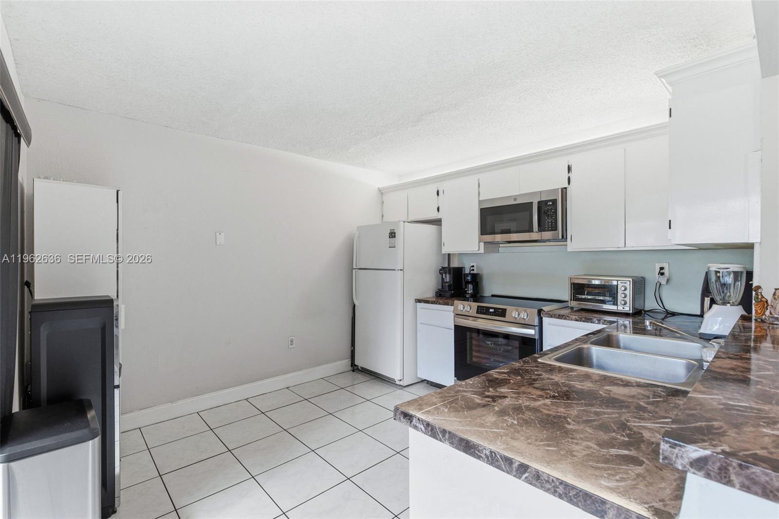 4726 Southwest 67th Avenue, Unit F6 Miami, FL 33155 - Photo 13 of 37 a kitchen with white cabinets and stainless steel appliances
