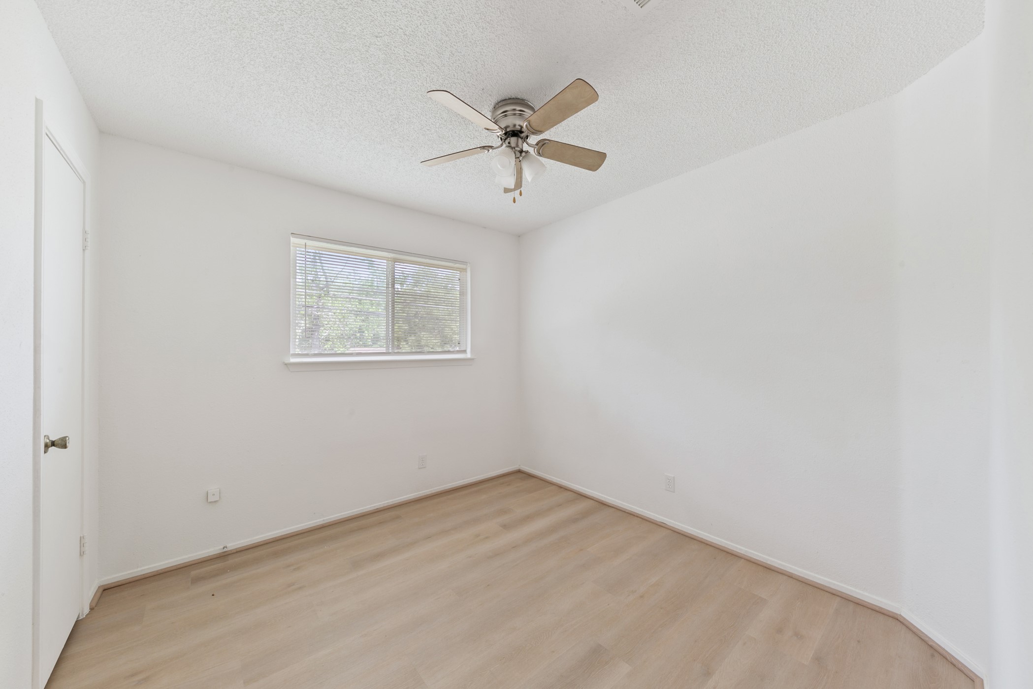 700 Lyle W Avenue, Unit B Cleveland, TX 77327 - Photo 7 of 17 This room features a clean, minimalist design with neutral walls and light wood flooring. It has a ceiling fan and a window for natural light, creating a bright and airy atmosphere. Perfect as a bedroom or home office.
