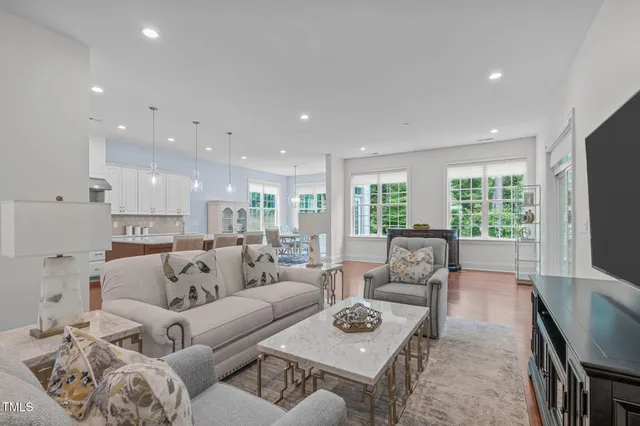 a living room with furniture flat screen tv and large windows