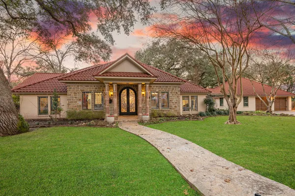 a front view of a house with a garden and trees