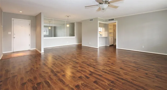 a view of an empty room with window and wooden floor