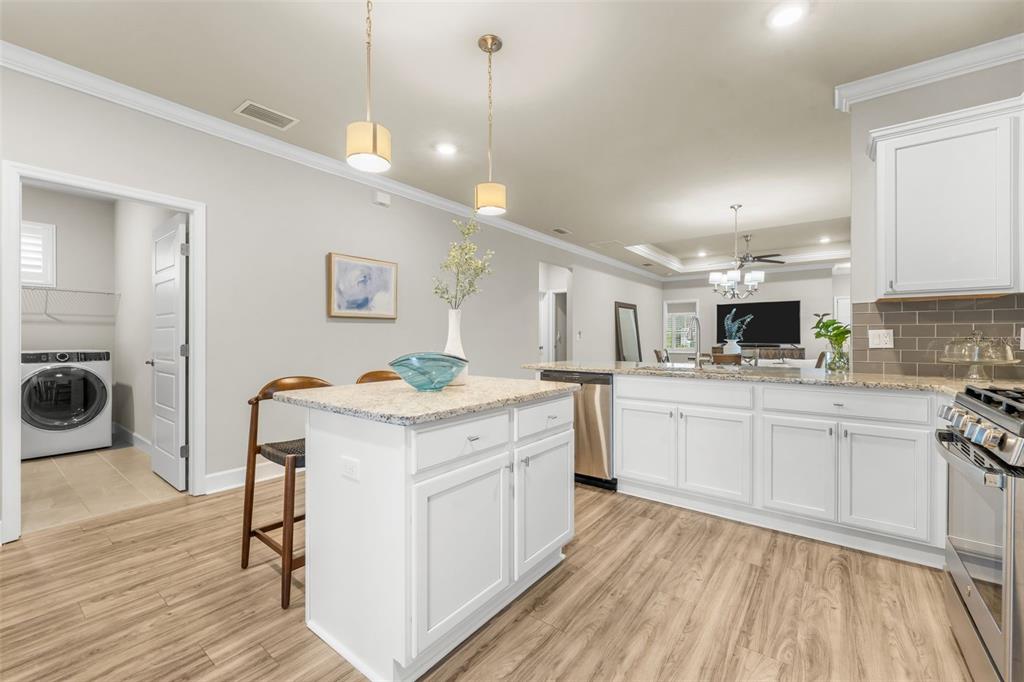 9437 Southwest 67th Lane Gainesville, FL 32608 - Photo 10 of 41 a kitchen with a stove a sink and white cabinets with wooden floor
