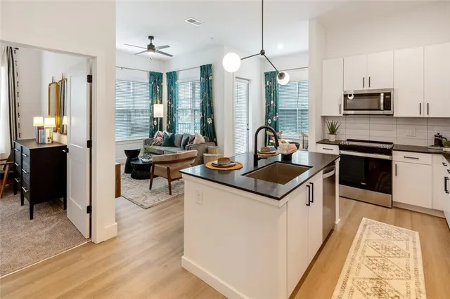 a kitchen with stainless steel appliances granite countertop a stove top oven a sink dishwasher a dining table and chairs with wooden floor