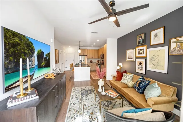 a living room with furniture ceiling fan and a large window