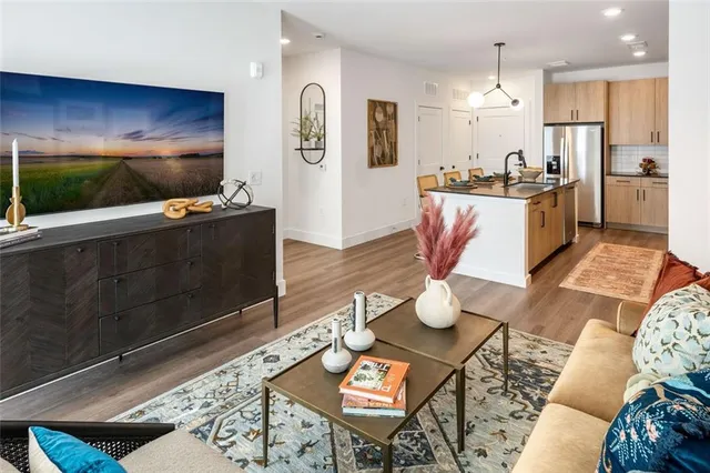 a kitchen with stainless steel appliances kitchen island granite countertop a refrigerator a stove a microwave oven with white cabinets and wooden floor