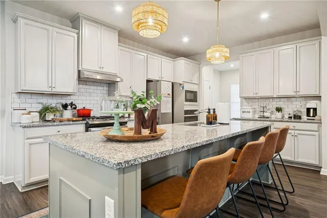 a kitchen with granite countertop stainless steel appliances a stove a sink and cabinets