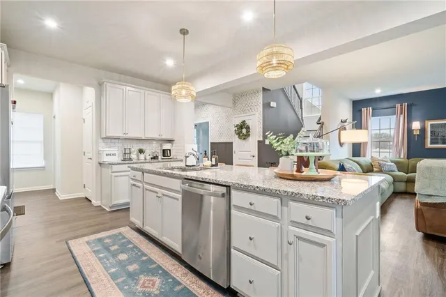 a kitchen with a sink dishwasher a stove a dining table and chairs with wooden floor