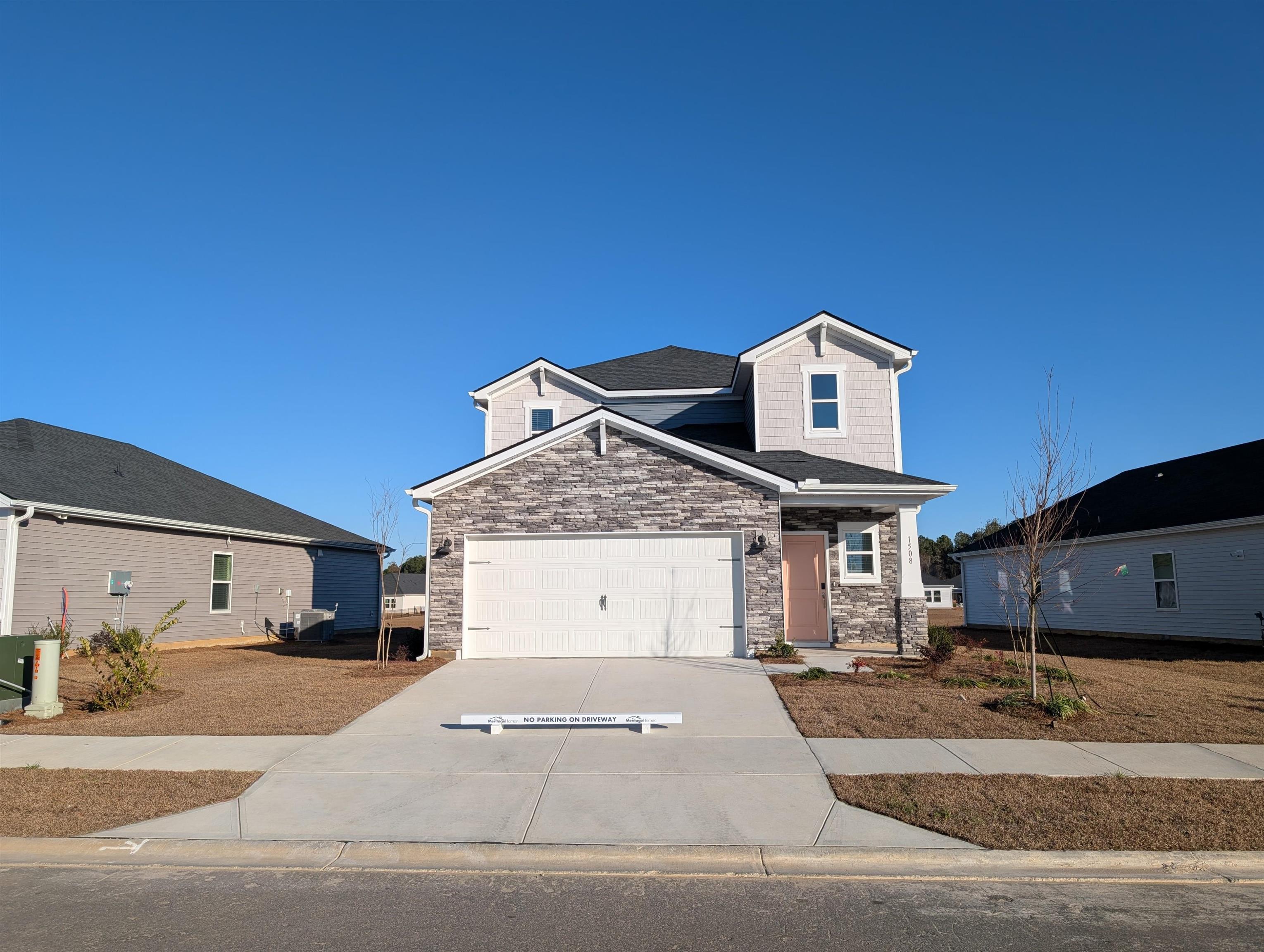 Craftsman-style house featuring stone siding, driveway, and a garage