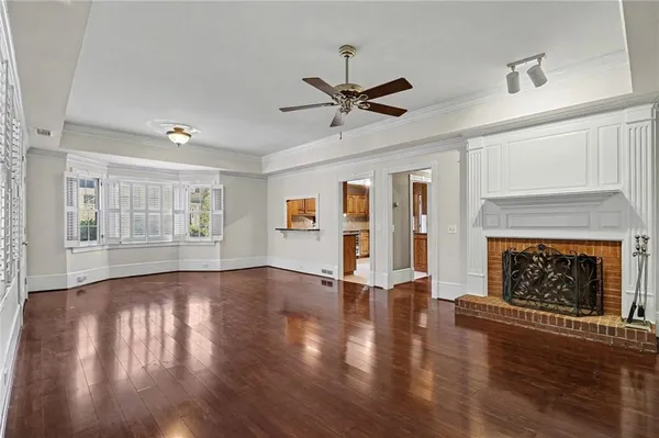 a view of an empty room with wooden floor fireplace and a window